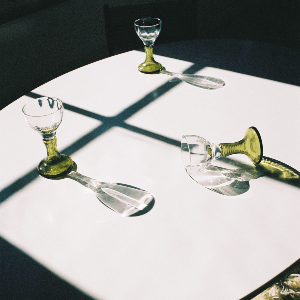 Vintage glassware casting shadows across a white table in the studio daylight