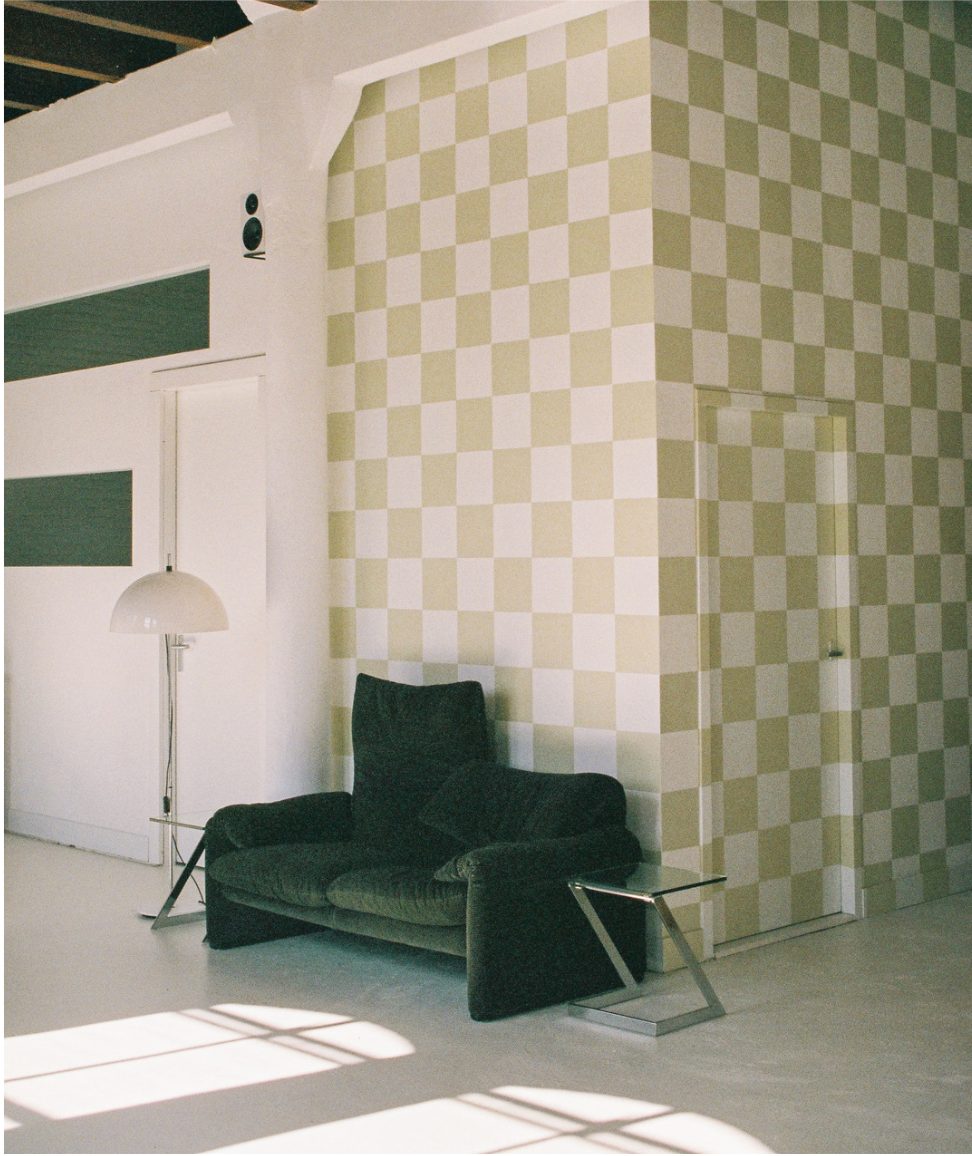A dark vintage armchair against the studio's checker wall