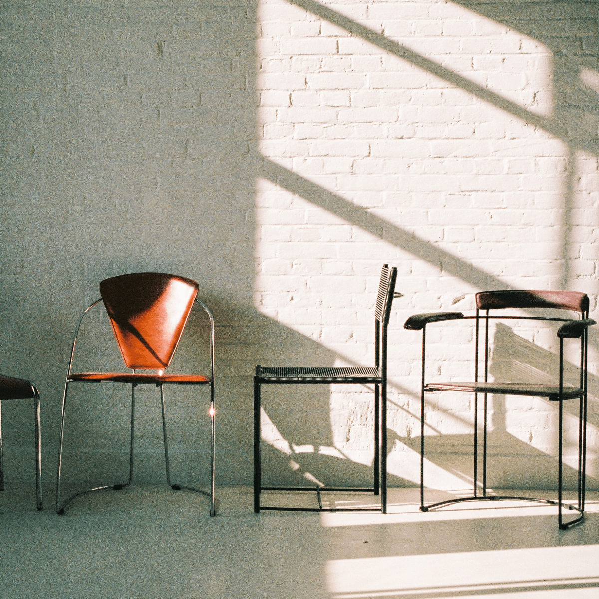 Studio interior — vintage chairs against white brick wall, natural daylight